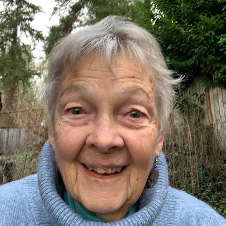 Headshot of Anne with a lavender sweater on and woods in the background